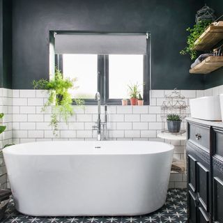 bathroom with dark blue and white tile wall bathtub white window and designed floor