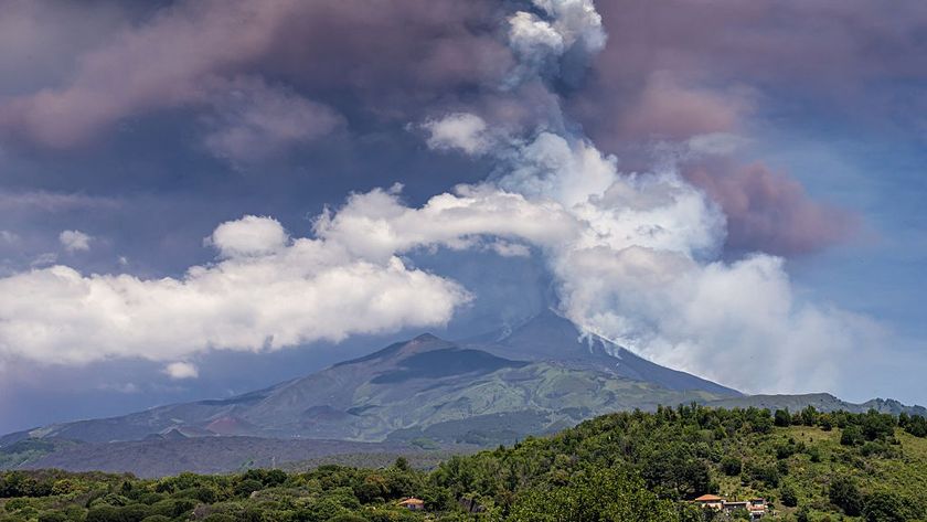 A view of Mount Etna erupting in June 2025. A large cloud of ash hangs over the volcano.