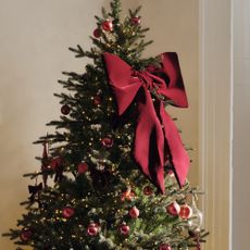 A Christmas tree decorated with red baubles and the M&S XL bow in red