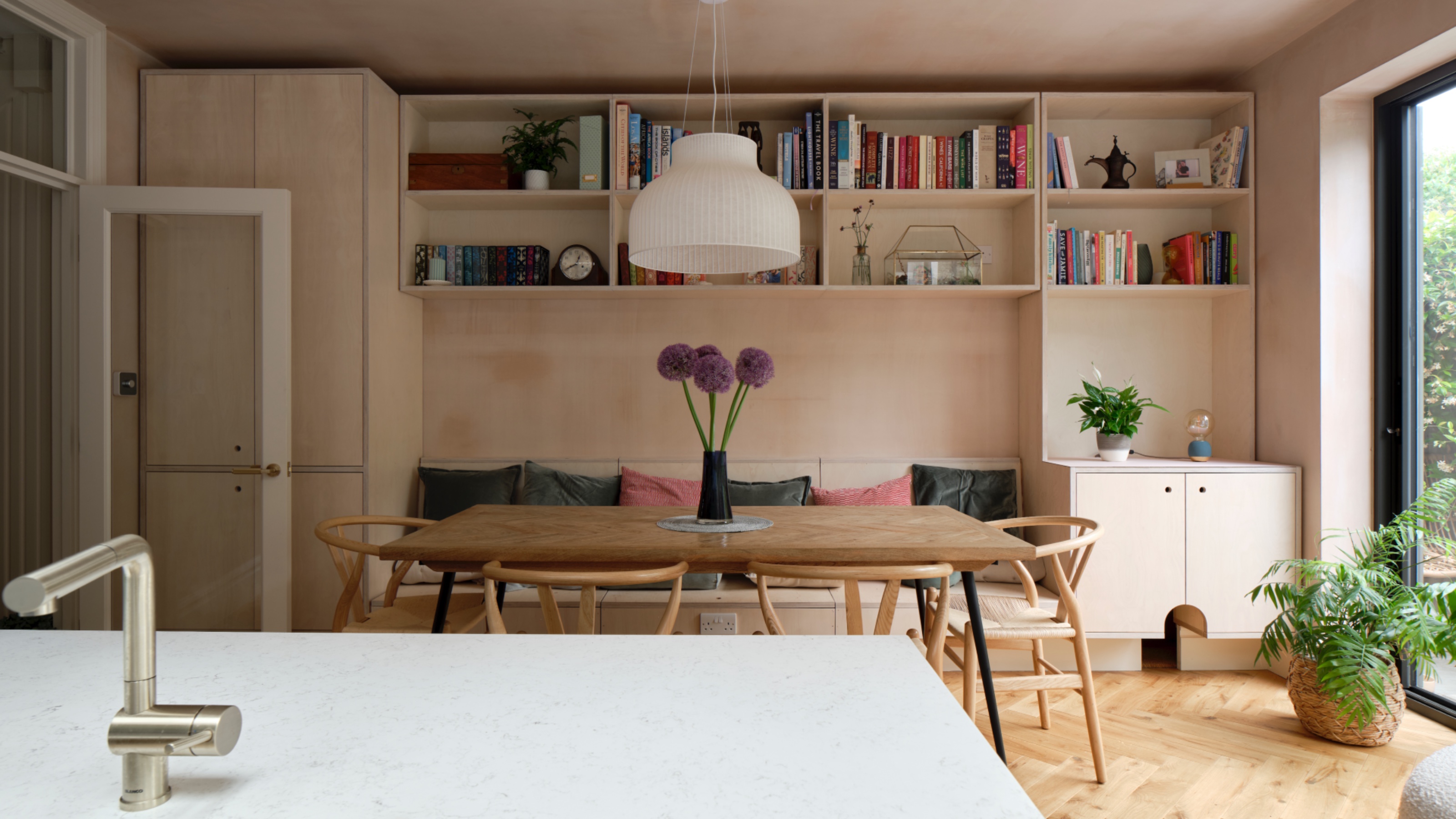 kitchen dining space with plywood cabinets/bench, dining table and view of island worktop