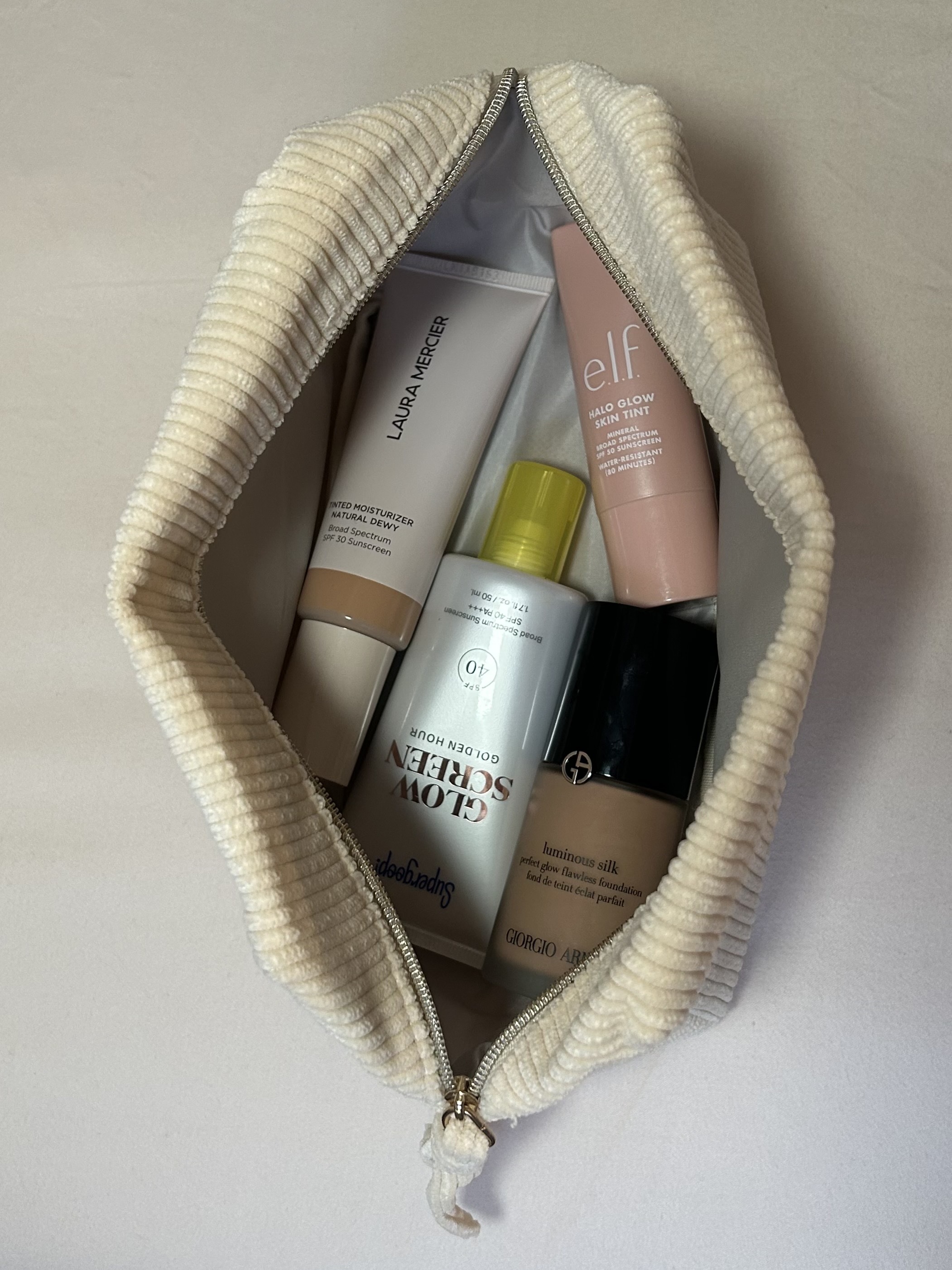 Alyssa Brascia's favorite foundations, tinted moisturizers, and sunscreens in a travel makeup bag.