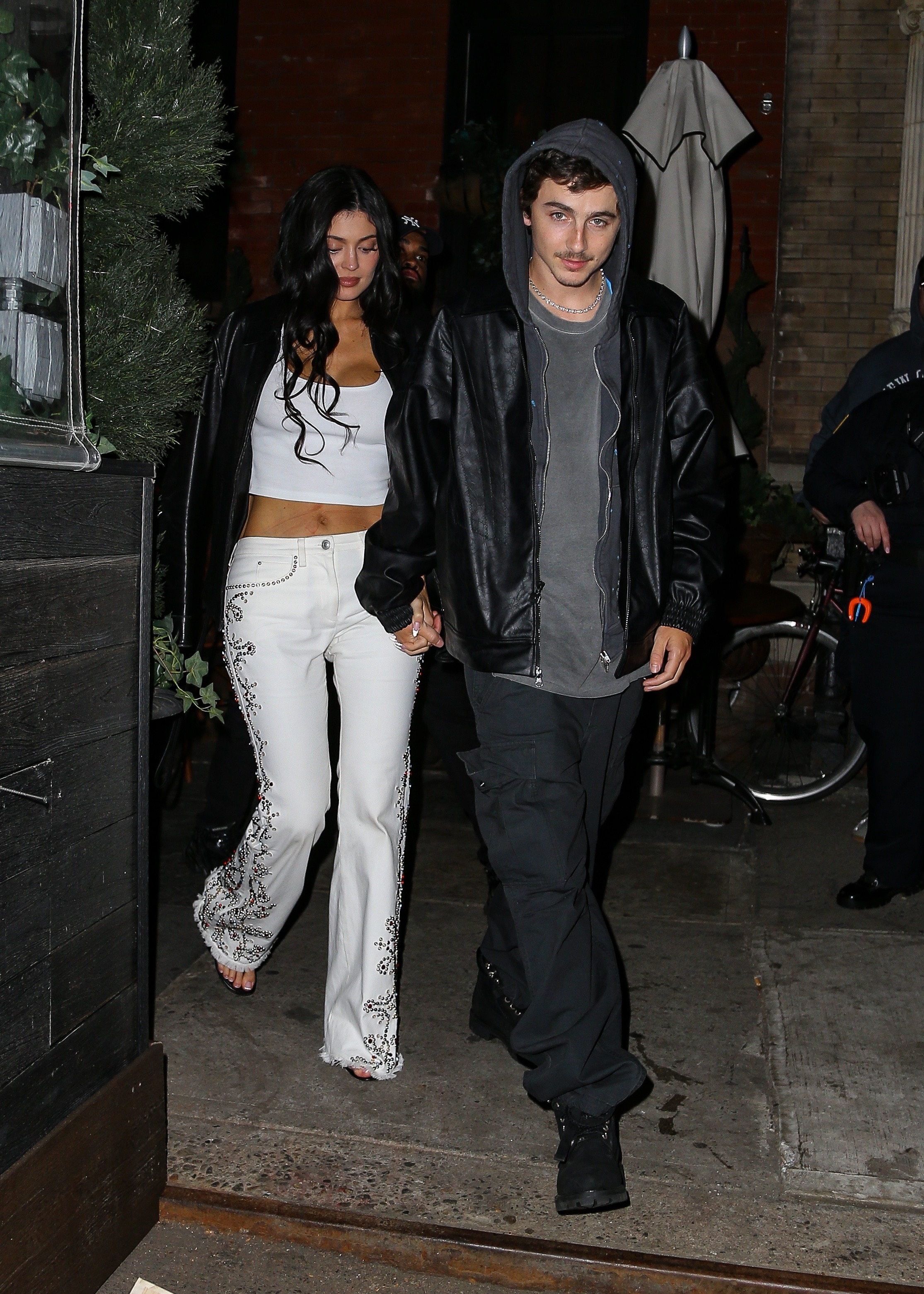 Kylie jenner wears a white tank with white studded jeans. Timothee wears a leather jacket and black pants.