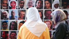 Menana Jabari (left), a relative of victims of the Grenfell Tower fire, looks at a wall displaying pictures of the 72 people killed in the blaze, at a press conference at the Royal Lancaster Hotel in London following the publication of the Grenfell Tower Inquiry