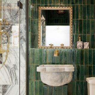 Green bathroom tiles stacked vertically next to marble shower