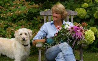 Dorian Winslow sits on a chair holding flowers next to a dog