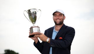 Scottie Scheffler holds the Travelers Championship trophy above his head