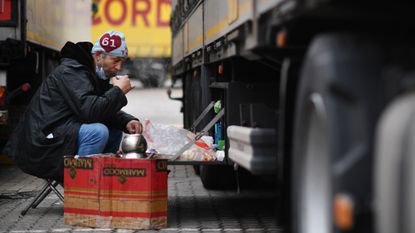 A truck drinks tea next to his freight truck at the Motis freight clearance centre.