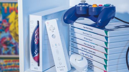 A picture of the Nintendo Wii and a stack of games with a GameCube controller on top of the game pile. 