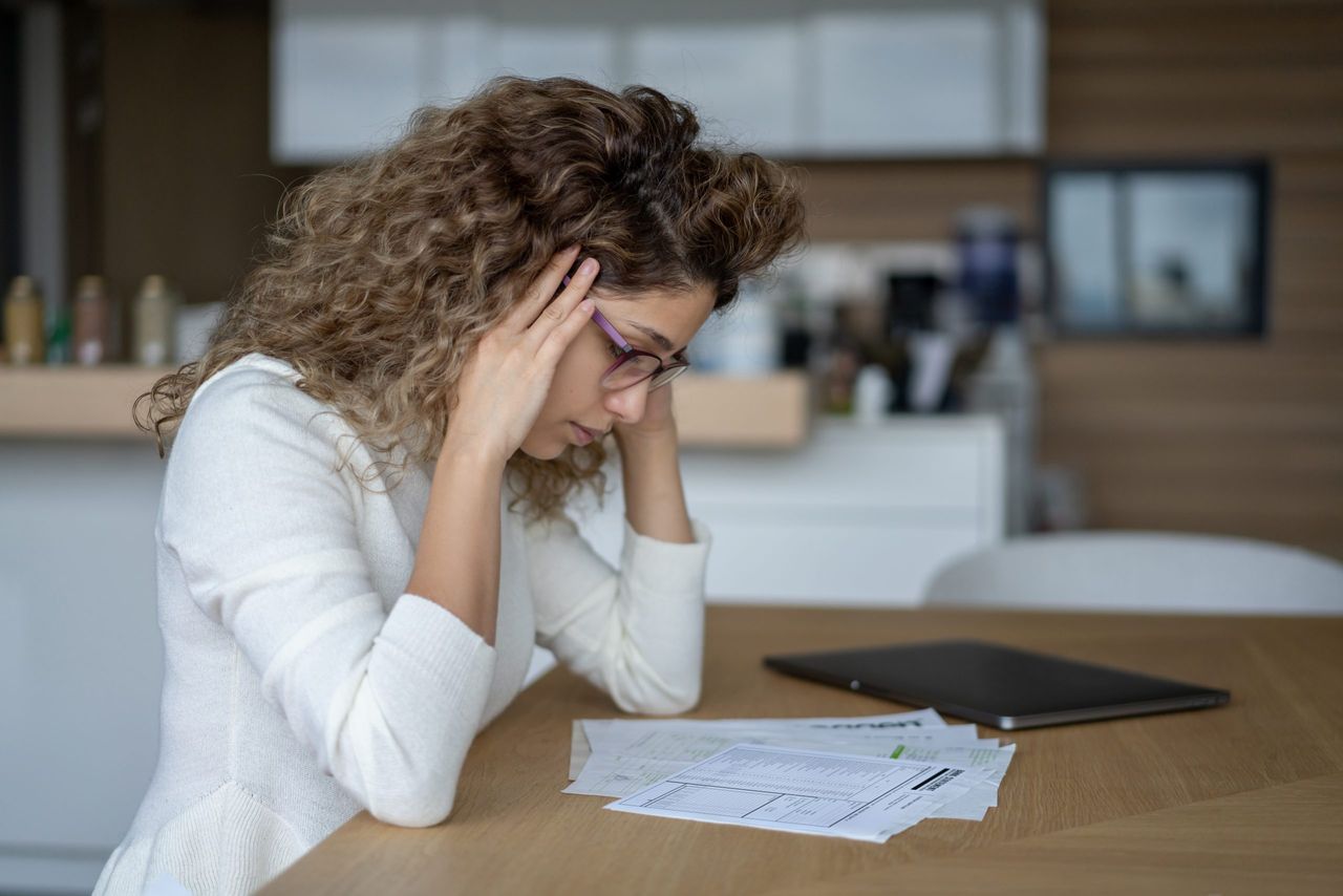 Woman at home looking worriedly at the utility bills