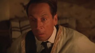 Jonathan Hyde sits upright with fear at night in The Mummy,