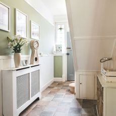 White and green painted hallway, taken from under the stairs and looking to a blue painted front door