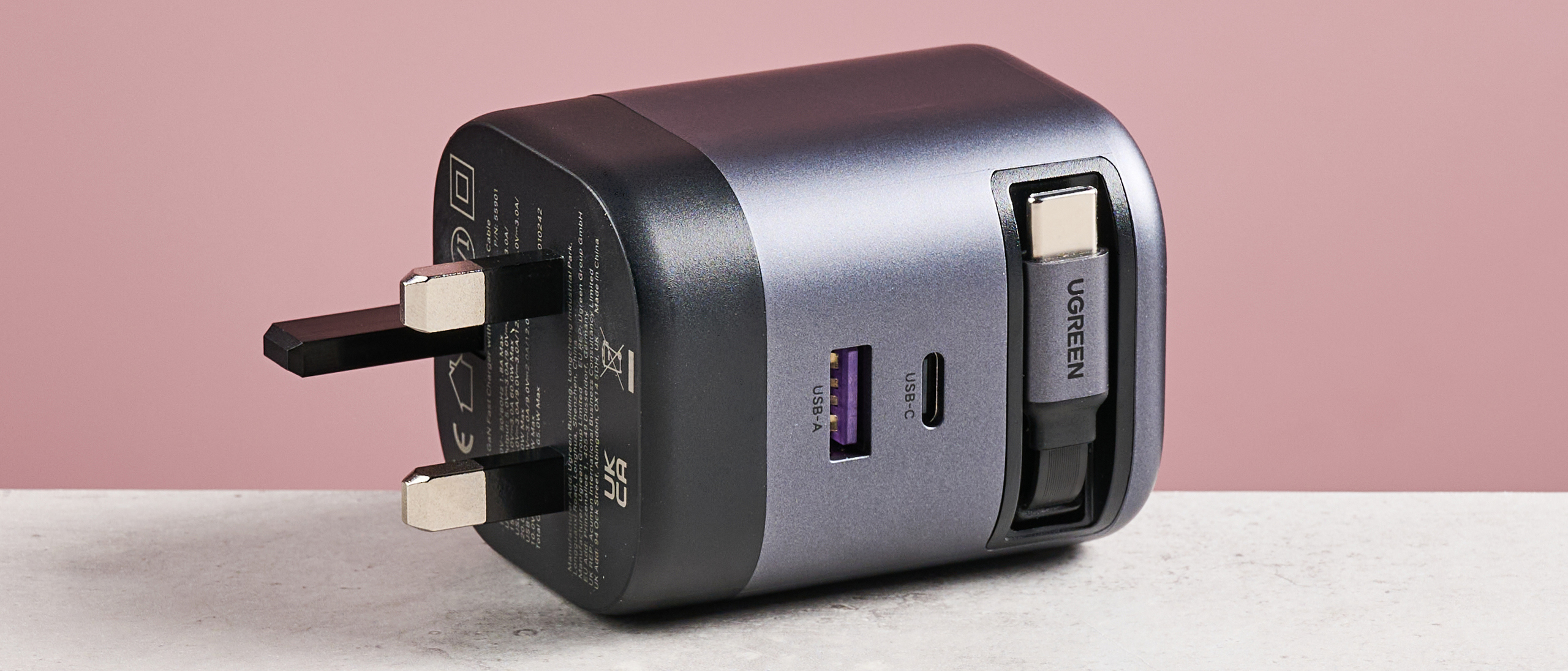 UGreen Nexode 65W Charger with Retractable USB-C Cable on its side against pink background