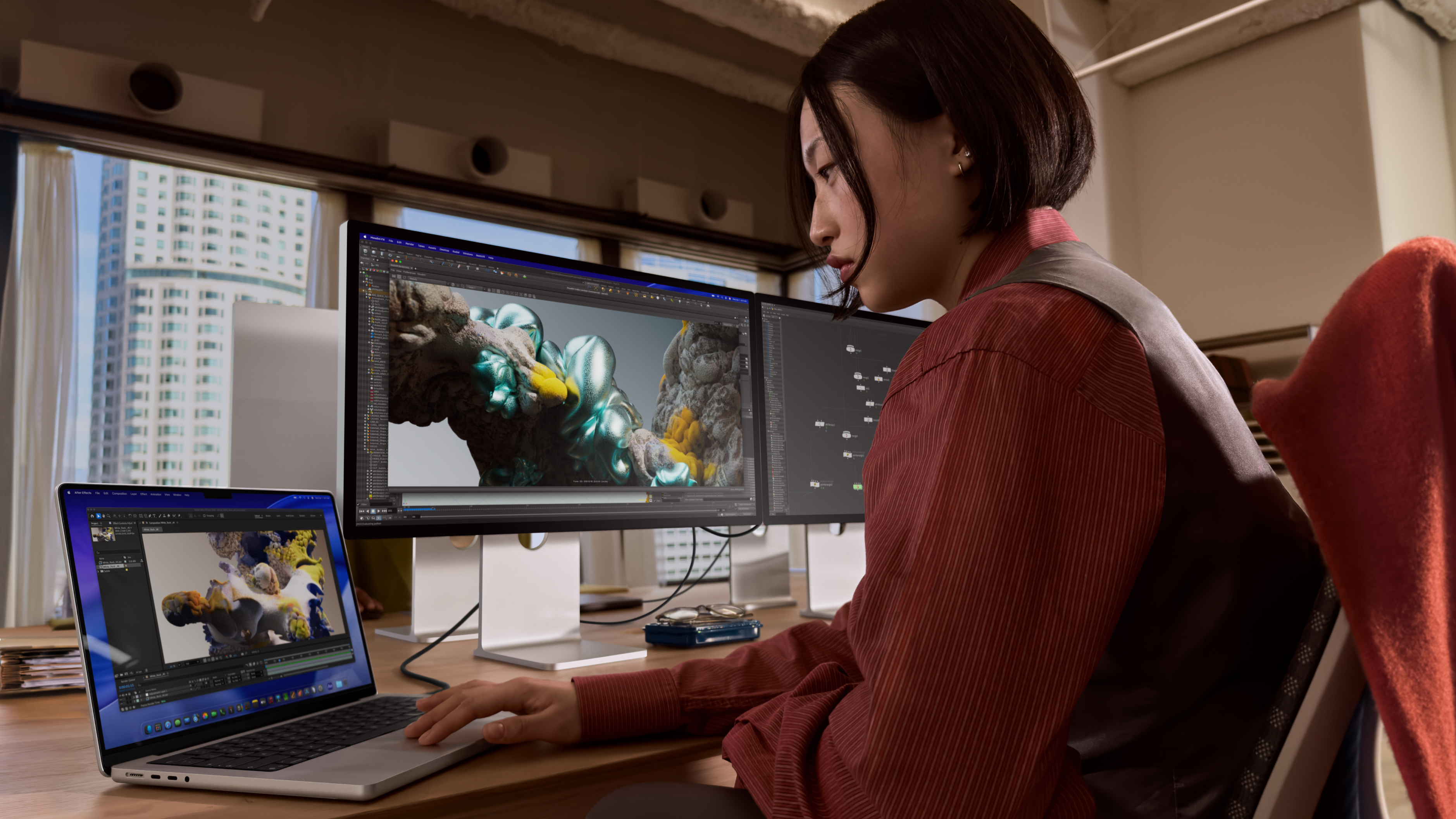 A person using their Apple MacBook Pro M5 Pro at a desktop in front of monitors
