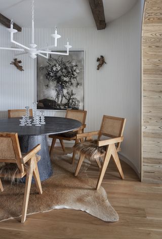A dining room with ribbed walls, round table and rattan chairs