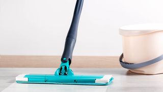 Flat mop on floor beside bucket