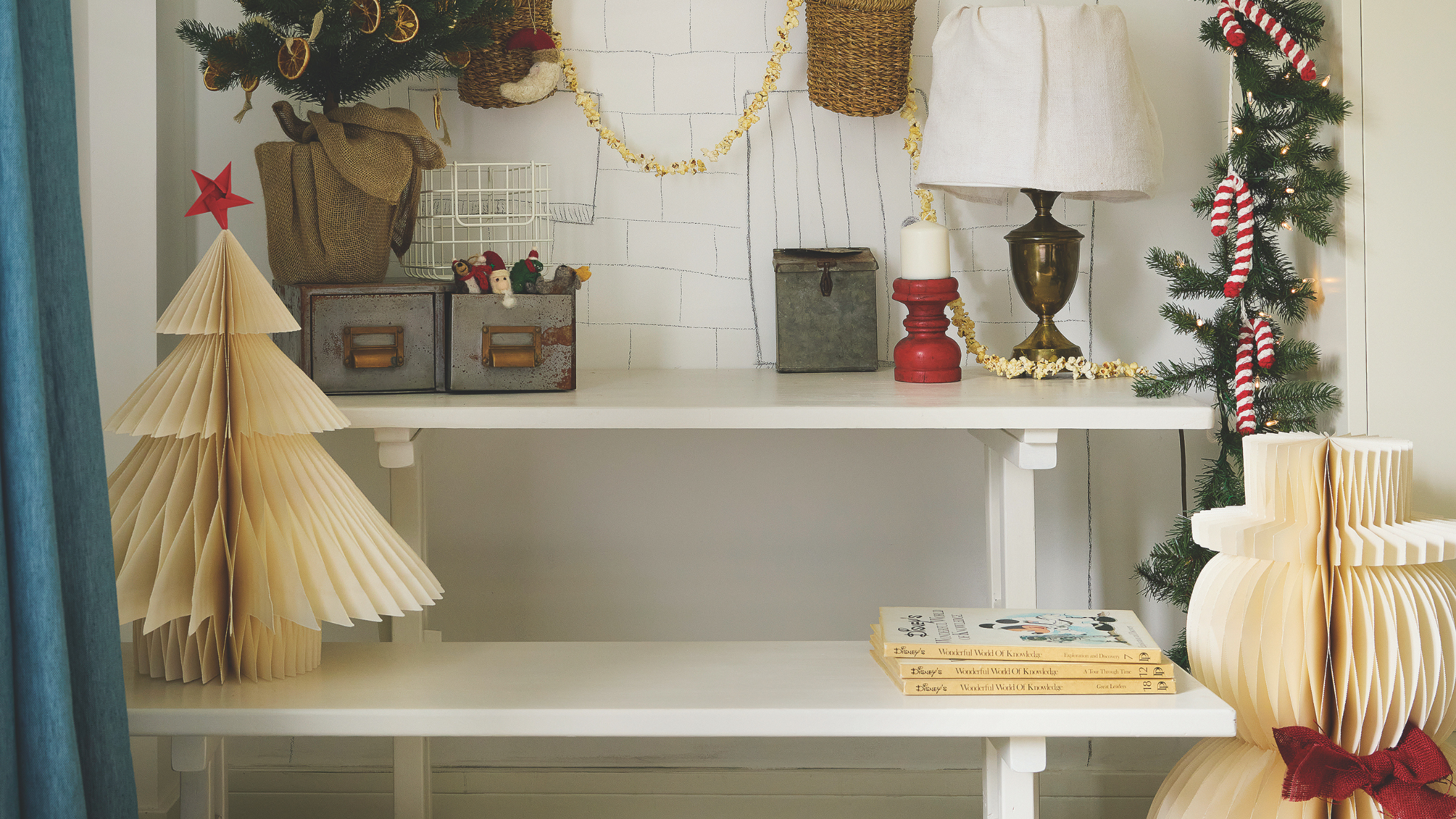 Paper chirstmas tre with red star on a shelf with other festive accessories.