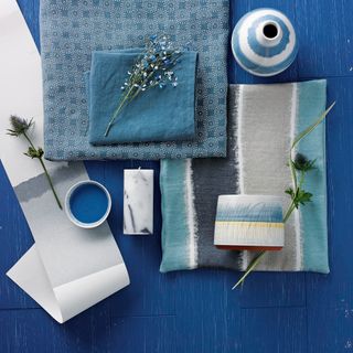 A flat lay with a blue background and various blue and white fabrics on top