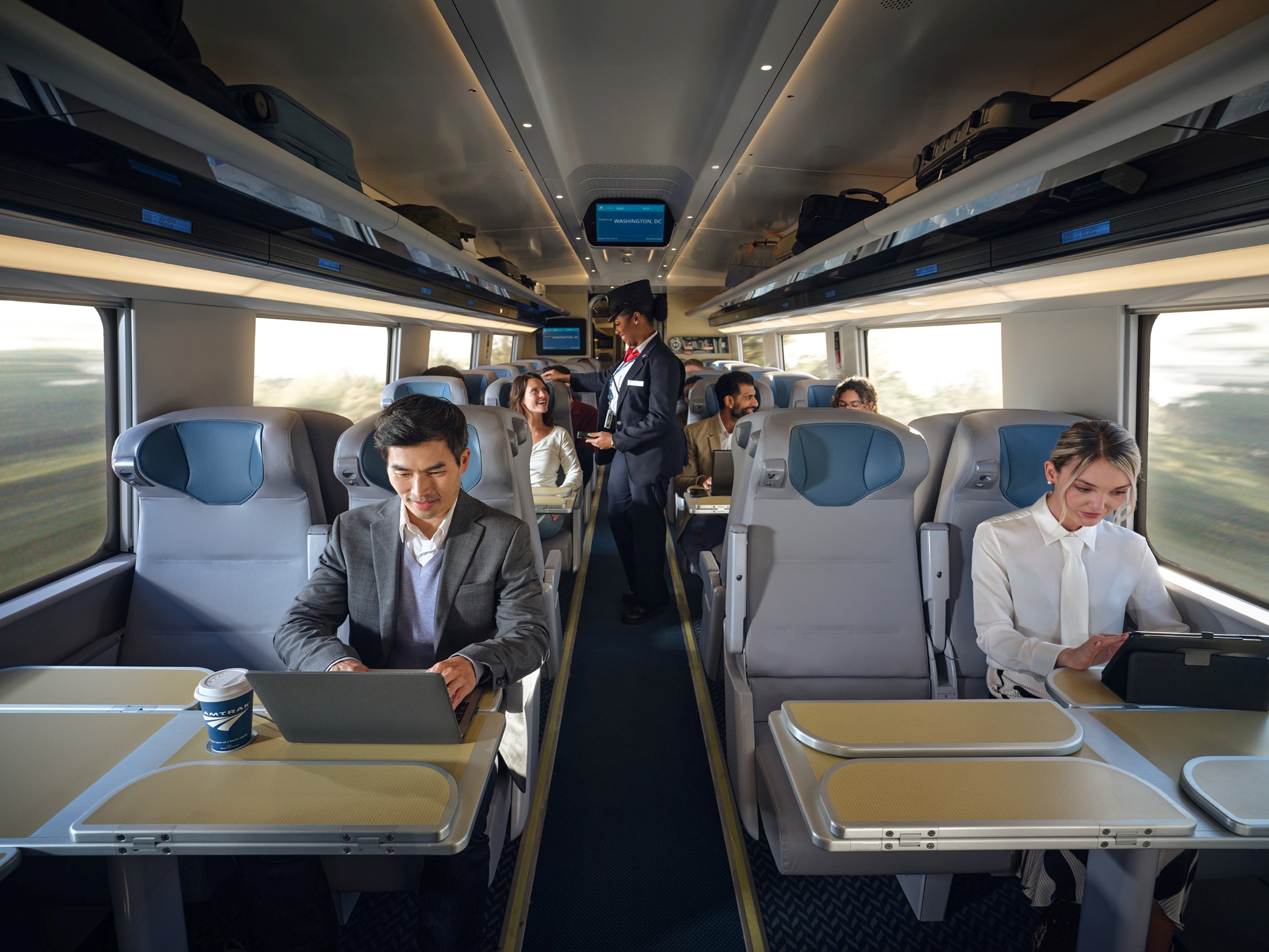 Passengers using laptops on an Amtrak Acela train.