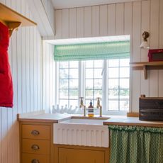 utility room with laundry area and butler sink with a green blind and yellow cabinetry