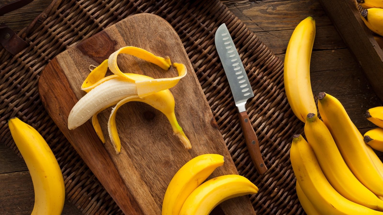 Bananas on a wooden chopping board with a knife