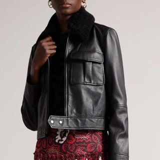 model wearing a black ted baker leather jacket with a shearling collar