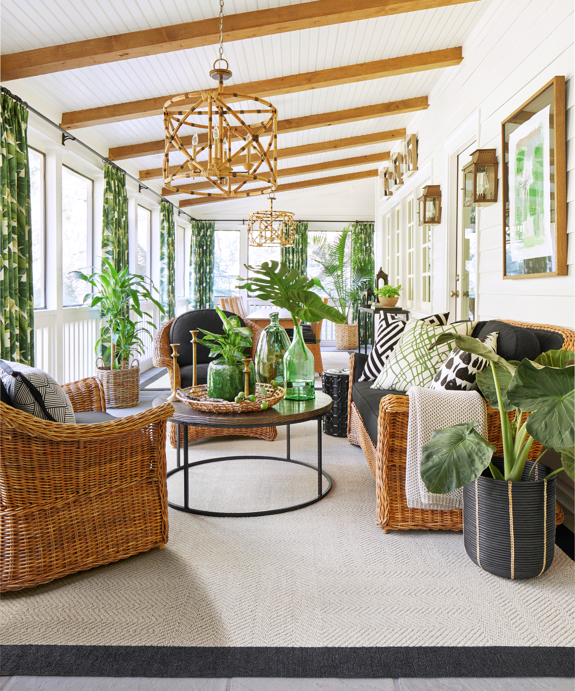 Fresh porch design with verdant, exotic greenery, rattan furniture, and jungle leaf design curtains.