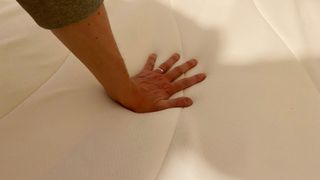 A hand pressing down on the Linenspa Memory Foam Hybrid mattress