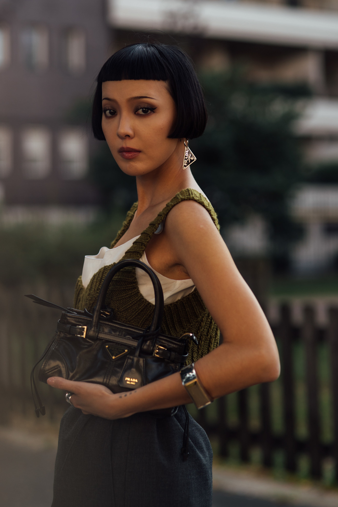 a woman with a black micro-bob holding a black leather purse