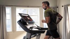 A man runnning on a running machine looking at the screen