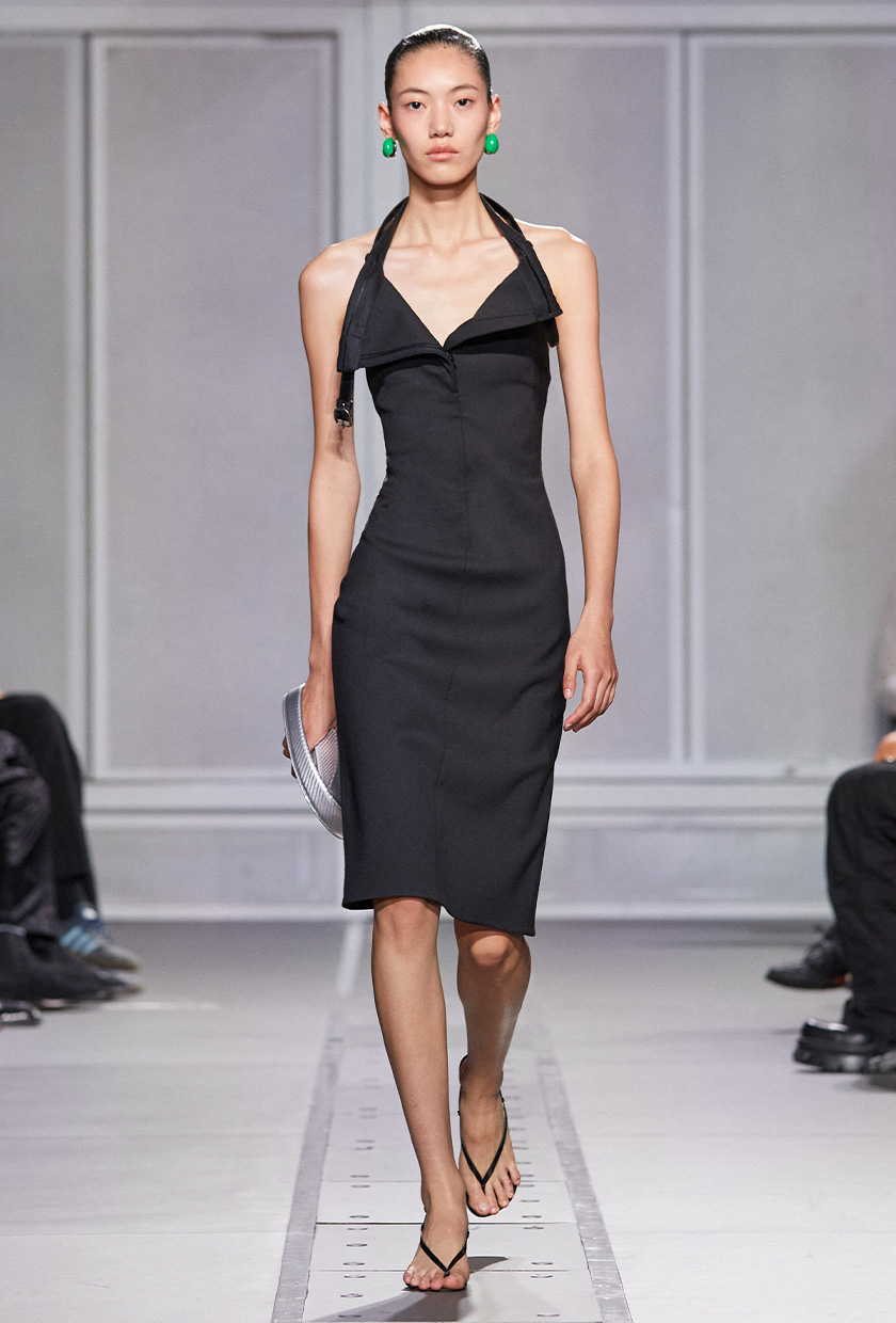 halter dress trend on Coperni's spring runway with a model wearing a fitted midi dress styled with black thong heels, green earrings, and a silver bag