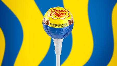 Meatball-flavored IKEA and Chupa-Chups lollipop in front of abstract blue and yellow background