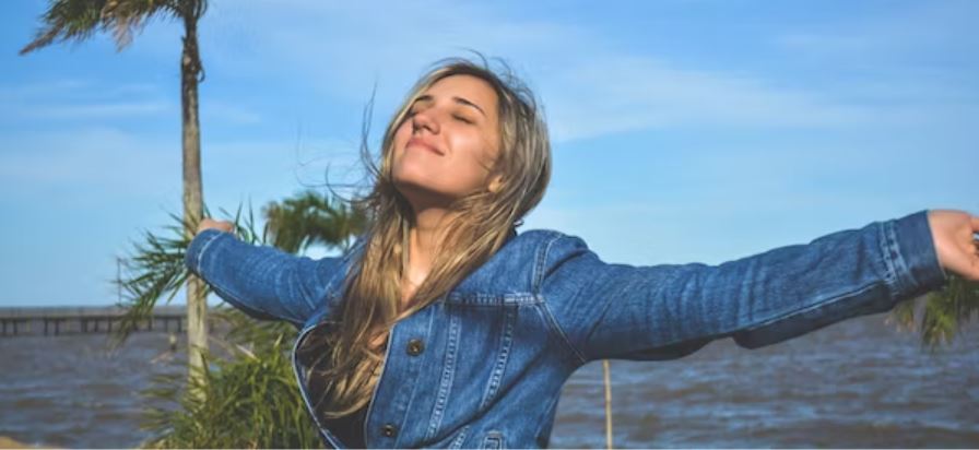 Woman smiling in the sun with her arms outstretched
