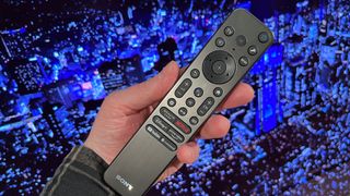 sony A95L QD-OLED TV remote control in hand in front of TV screen