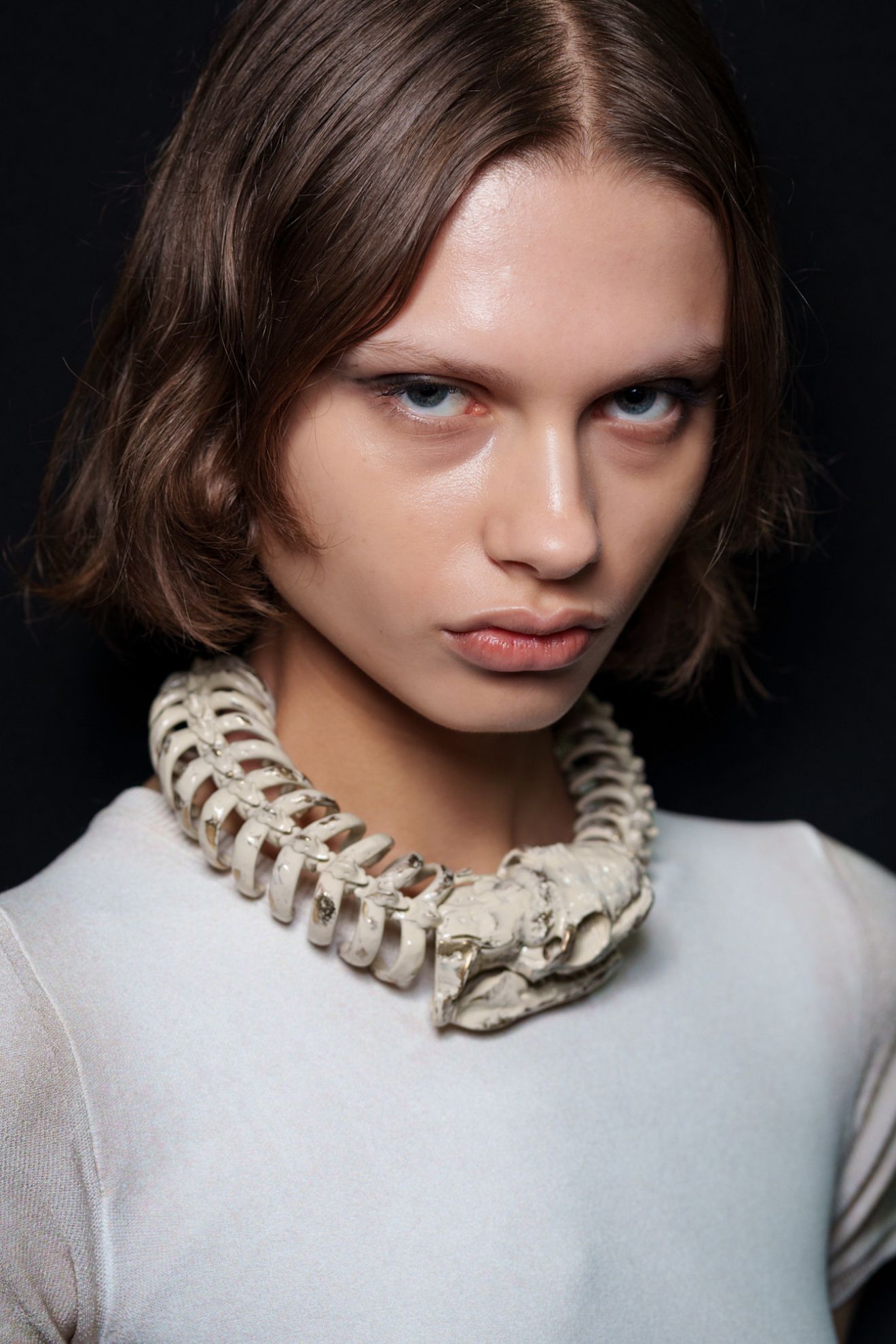 A model in the DIESEL SS26 show wearing a white t-shirt and a statement necklace with a choppy bob haircut and glowing skin