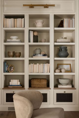 a neutral living room with bookshelves filled with objects and books