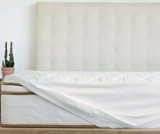 Saatva Waterproof Mattress Protector on a bed against a white wall.