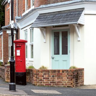 brick house exterior with a white door and windows red post box