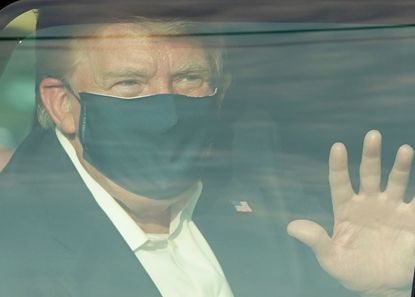 Donald Trump waves from his motorcade.