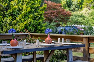 An outdoor dining table sits on a raised platform overlooking the garden