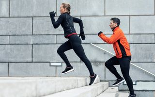 a photo of a male runner and female runner running up stairs
