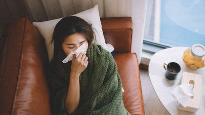 A woman with a cold lying on the sofa ill