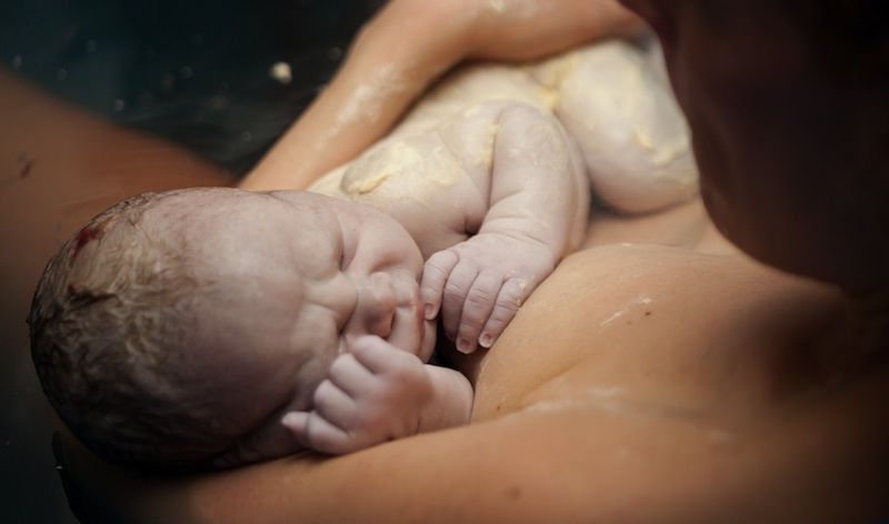 A newborn baby in mother&#039;s arms.