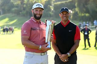 Jon Rahm holds the Genesis Invitational trophy with Tiger Woods next to him