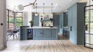 large kitchen island in open plan kitchen diner with blue cabinets and wooden flooring