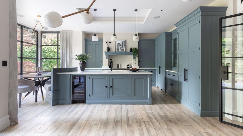 large kitchen island in open plan kitchen diner with blue cabinets and wooden flooring