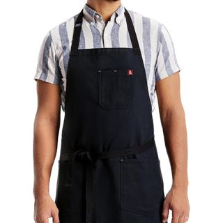 A person wearing a blue and white striped shirt and a dark blue Hedley & Bennett apron