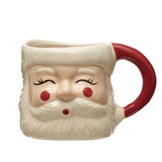 A mug with a Santa face with closed eyes smiling, with red cheeks and a red handle