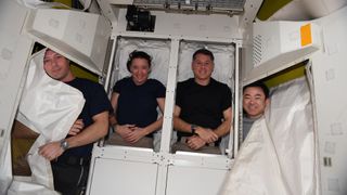 Astronauts at the International Space Station pose with a newly installed cargo compartment inside the Quest airlock, on Aug. 27, 2021. From left to right: ESA astronaut Thomas Pesquet, NASA astronauts Megan McArthur and Shane Kimbrough, and JAXA astronaut Akihiko Hoshide.