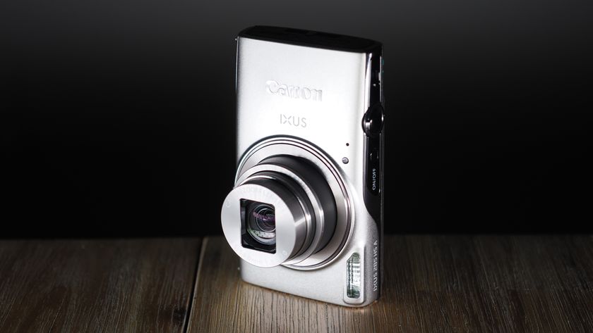 Canon Ixus 285 HS A on a wooden surface against a dark background