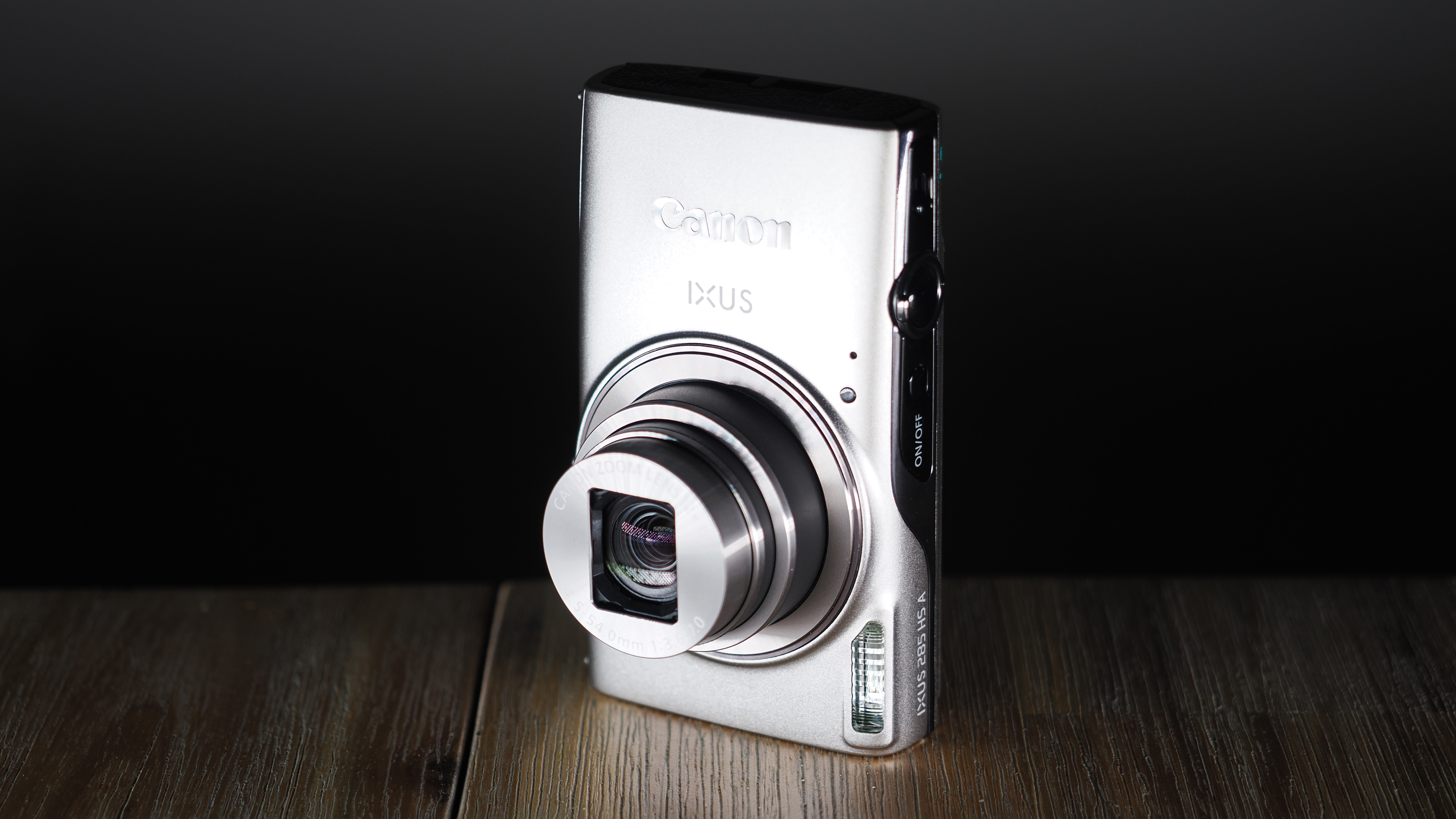 Canon Ixus 285 HS A on a wooden surface against a dark background